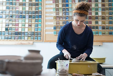 Female SJNY student creating a bowl using the potter's wheel