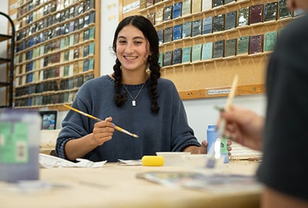 SJNY Student painting ceramics and smiling